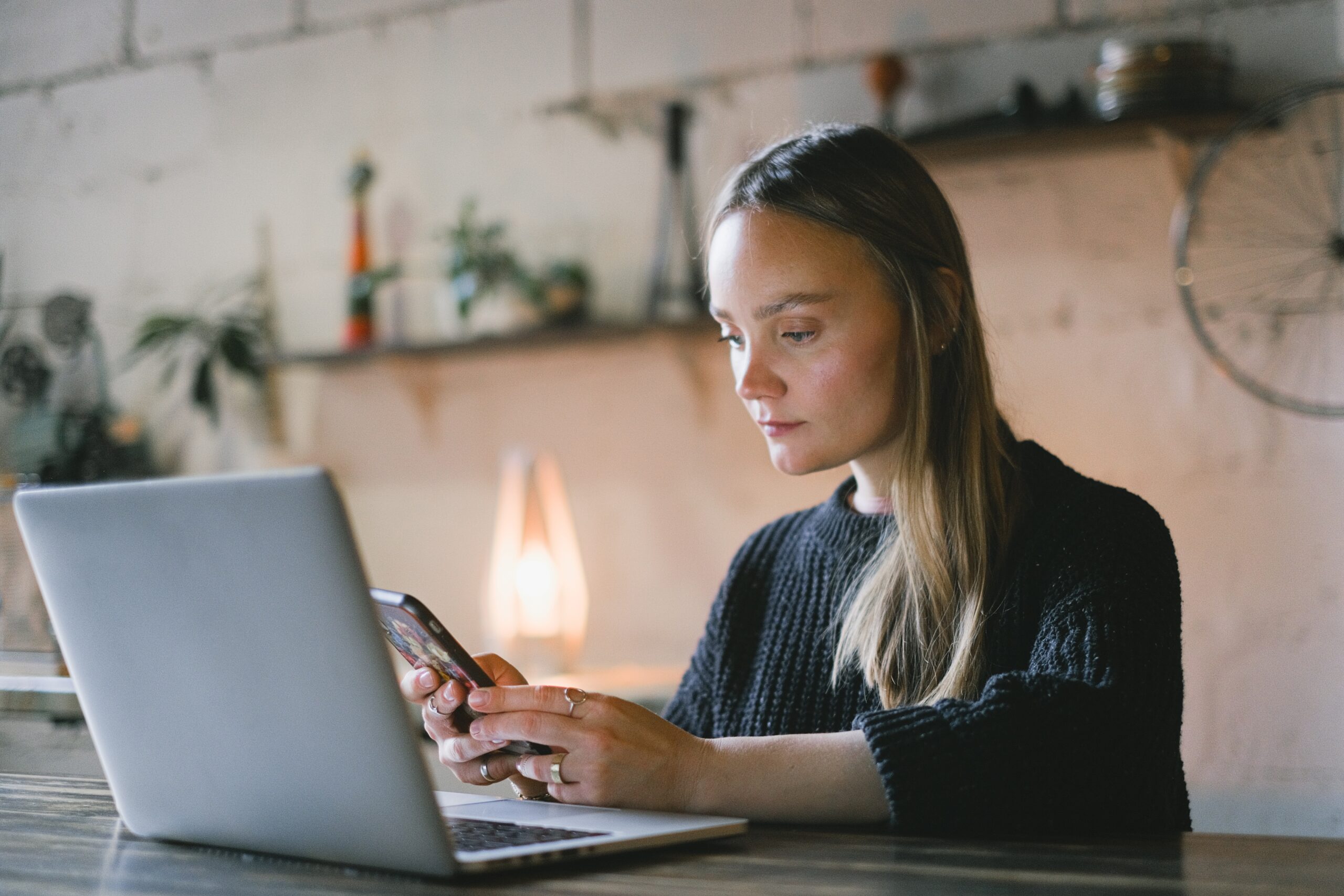 woman looking at her phone and laptop